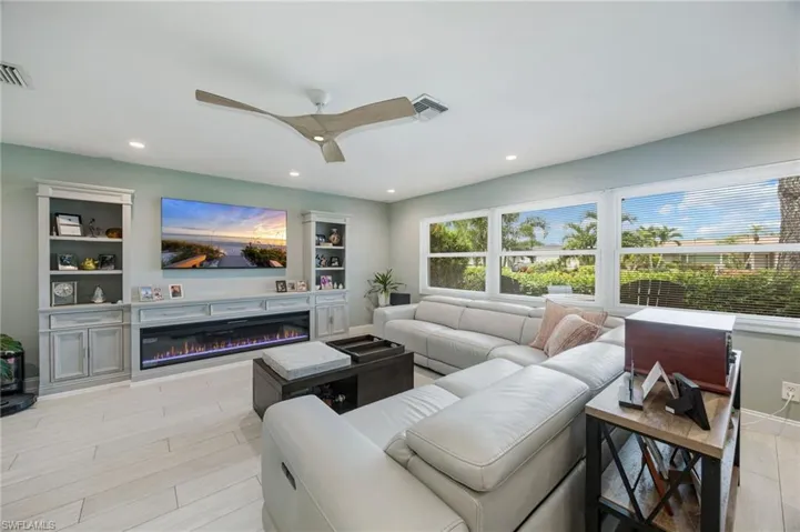 Recessed lighting throughout, built-in entertainment center with fireplace, ceiling fan, multiple windows with blinds, and tile flooring