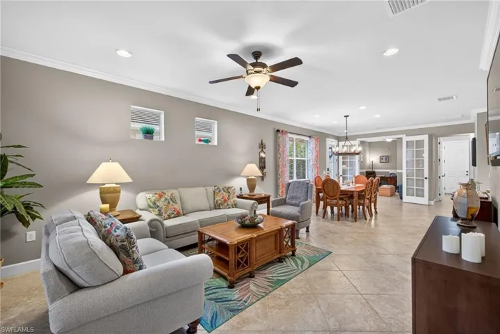 Spacious living area featuring tile flooring, crown molding, recessed lighting, and a ceiling fan