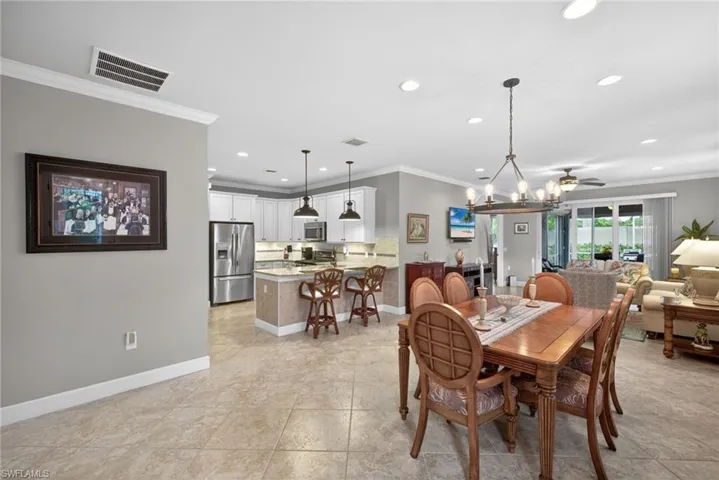 Open-concept living area featuring tile flooring, crown molding, and recessed lighting