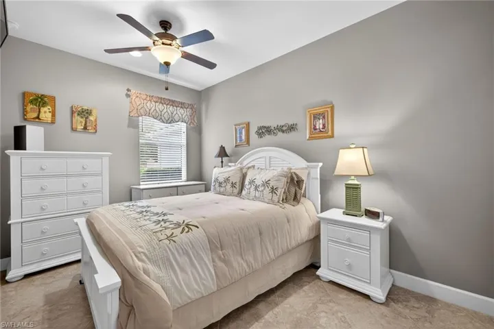 Neutral-toned interior with tile flooring, a window featuring blinds and a valance, a ceiling fan with integrated lighting, and white baseboards