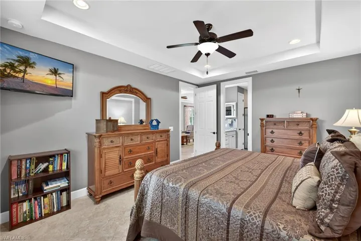 Tray ceiling with recessed lighting and a ceiling fan, featuring light gray wall paint and tile flooring