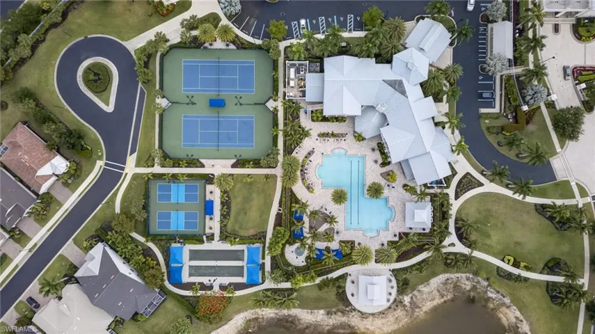 Aerial view showcasing a comprehensive amenity center with multiple tennis courts, two swimming pools, and extensive manicured landscaping