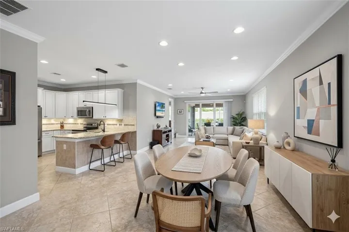 Spacious open-concept interior featuring light gray wall tones, crown molding, and large-format tile flooring
