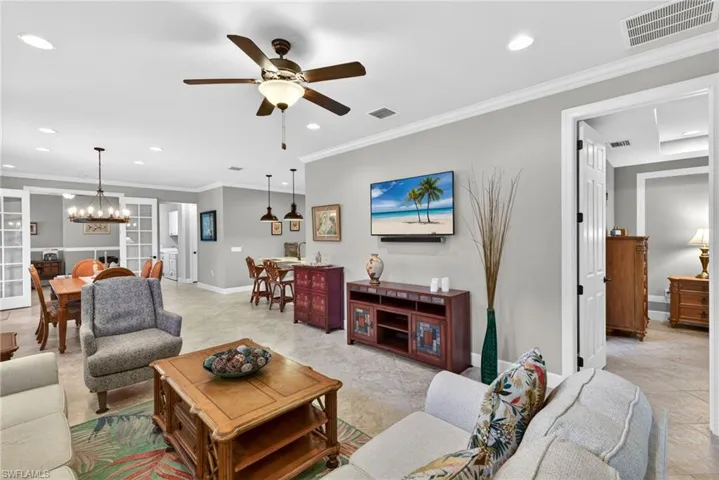 Open-concept living space featuring neutral gray walls, recessed lighting, and crown molding