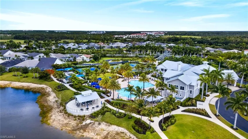 Expansive community amenity center featuring a large swimming pool, multiple sports courts, and a two-story clubhouse with a gray exterior and white trim