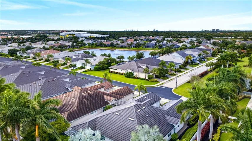 Aerial perspective showcasing a residential community with varied rooflines and a central pond