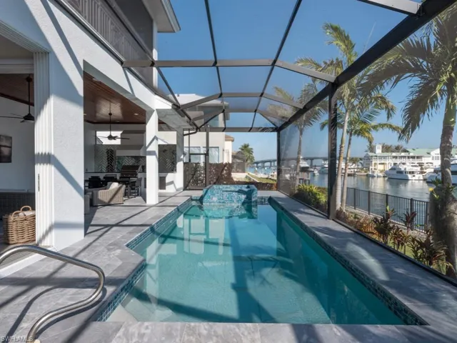 View of swimming pool with a lanai, ceiling fan, a patio area, area for grilling, and a water view