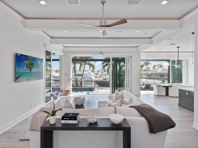 Living room with beamed ceiling, ornamental molding, a water view, ceiling fan, and light hardwood / wood-style flooring