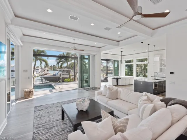 Living room with hardwood / wood-style floors, ceiling fan, beamed ceiling, crown molding, and sink