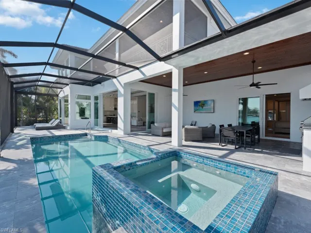 View of swimming pool with glass enclosure, ceiling fan, a patio area, an outdoor hangout area, and an in ground hot tub