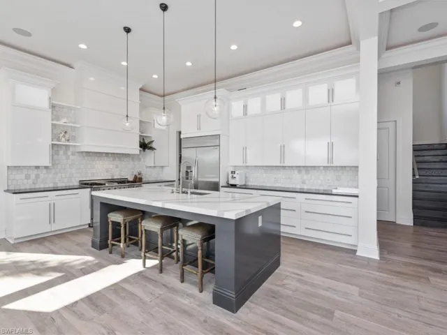 Kitchen featuring built in fridge, white cabinetry, and a kitchen island with sink