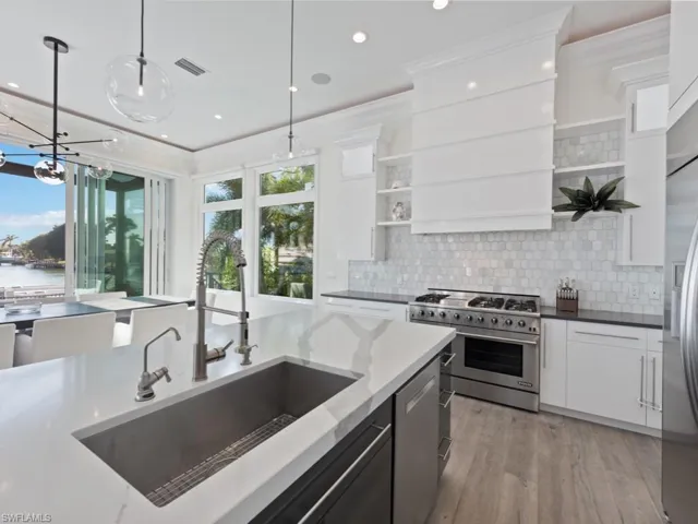 Kitchen with pendant lighting, sink, white cabinetry, stainless steel appliances, and dark stone counters
