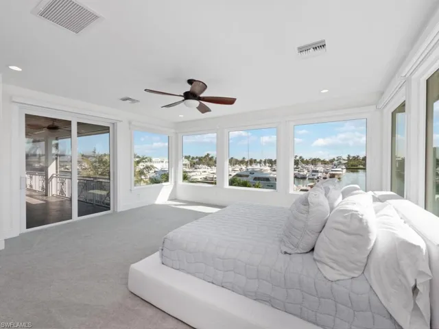 Carpeted bedroom with ceiling fan, access to outside, and a water view