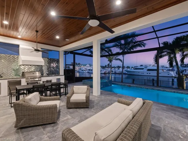 Pool at dusk with ceiling fan, area for grilling, grilling area, a lanai, and a patio