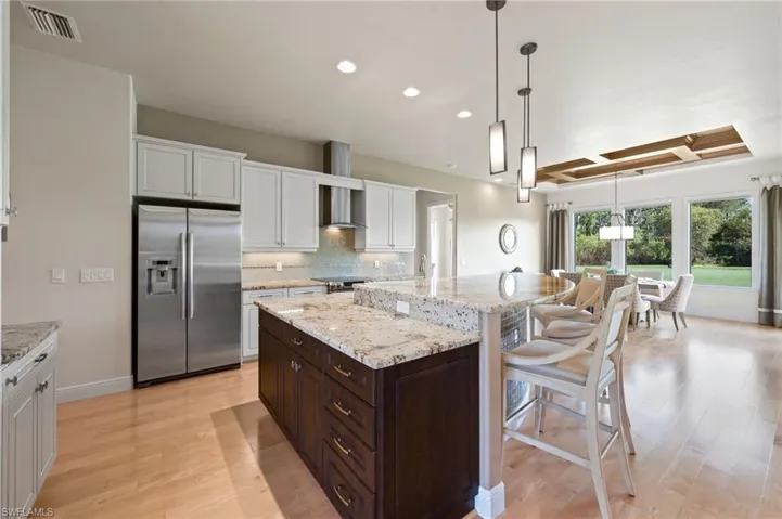 View of Island with Breakfast bar, stainless refrigerator.