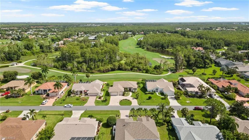 View of home, lawn course and wooded area behind the home.
