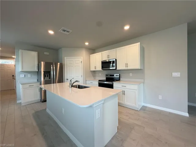 Kitchen featuring appliances with stainless steel finishes, a sink, baseboards, light countertops, and recessed lighting