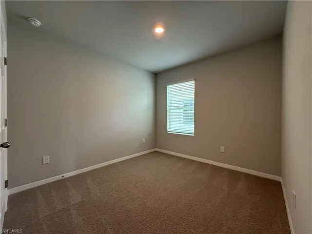 Carpeted spare room with baseboards and a smoke detector