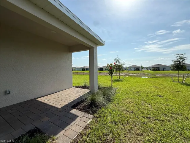 View of green lawn featuring a patio area and a water view