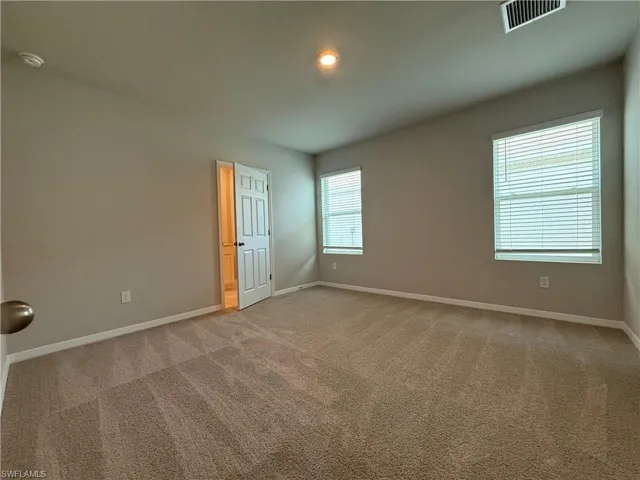 Spare room with light carpet, baseboards, and a smoke detector