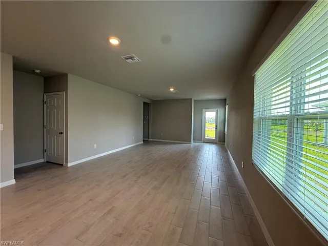 Unfurnished room with wood finished floors, baseboards, and recessed lighting
