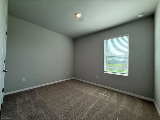 Carpeted spare room with baseboards and a smoke detector