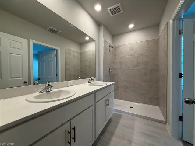 Bathroom featuring double vanity and tiled shower