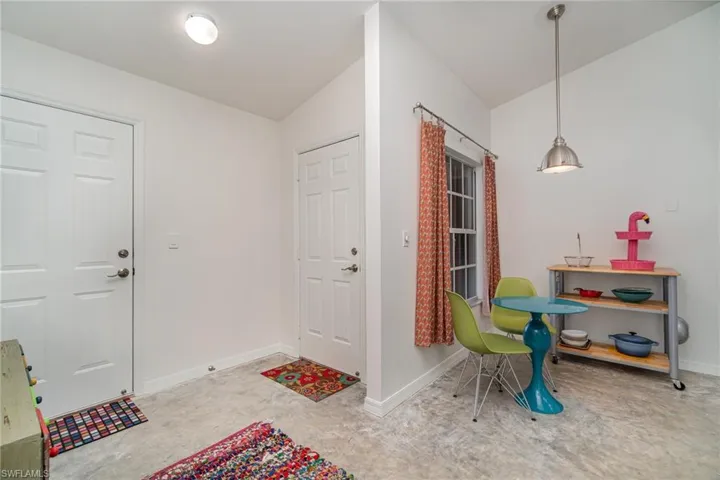 View of front door and garage door, concrete floor and breakfast area in kitchen