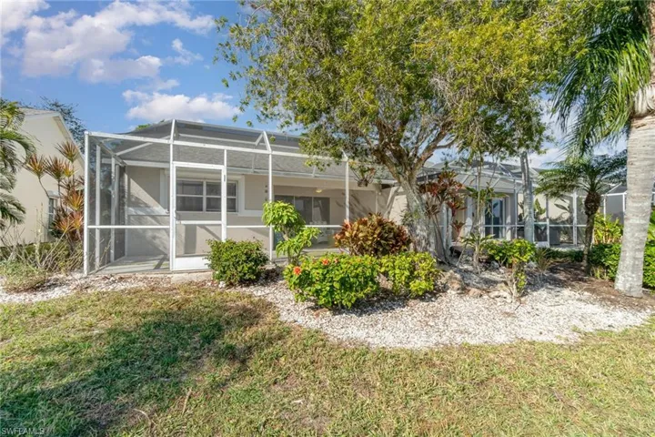 Back of property featuring a yard and greenery