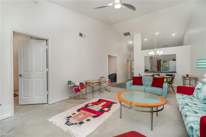 Living room with vaulted ceiling, modern ceiling fan, concrete floor and freshly painted