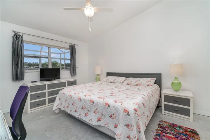 Primary Bedroom with vaulted ceiling, concrete floor, and crank window shutter
