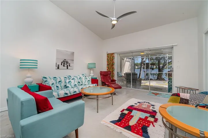 Living room featuring ceiling fan, vaulted ceiling, and lake view