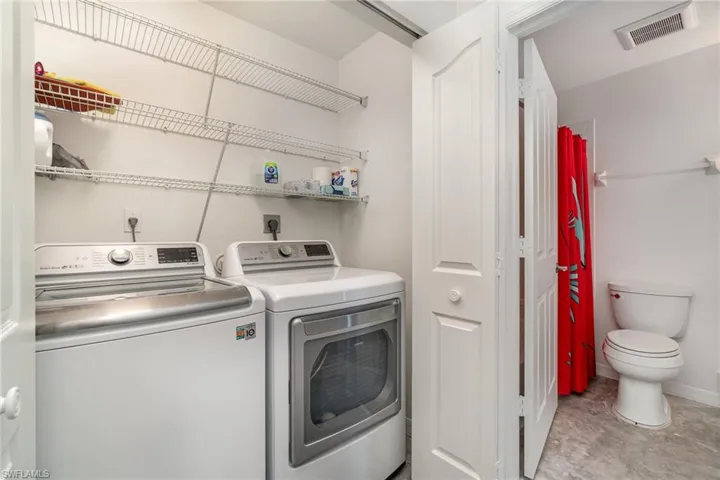 Laundry area featuring washing machine and dryer with shelving and doors