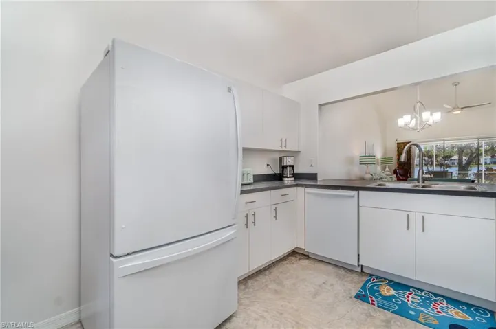Kitchen with white appliances, sink, and white cabinets
