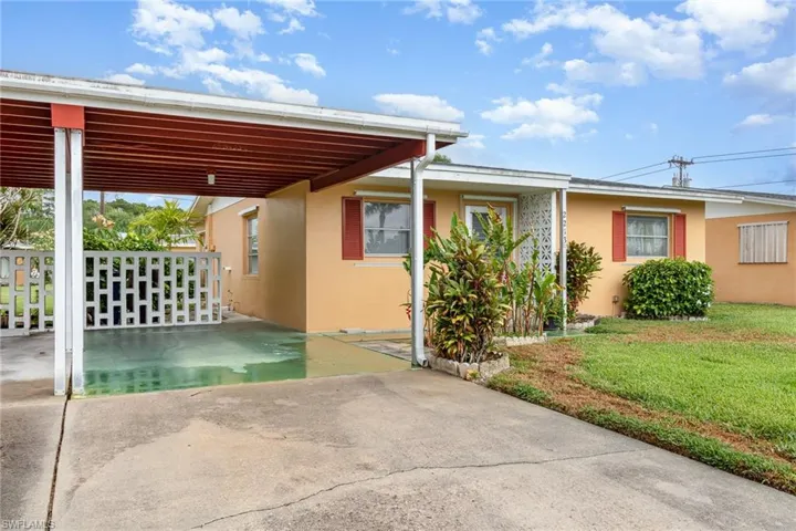 View of front of home with stucco siding, a front lawn, and a carport
