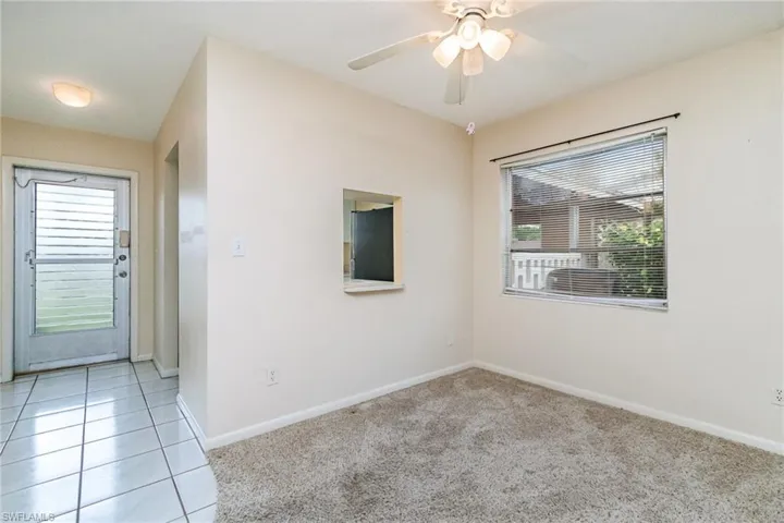 Empty room with a ceiling fan, light carpet, and light tile patterned floors