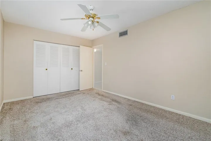 Unfurnished bedroom with carpet, a closet, and a ceiling fan
