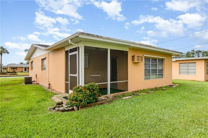 View of side of home with a yard, stucco siding, and a sunroom