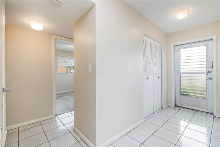 Corridor featuring light tile patterned flooring and baseboards