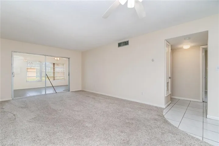 Spare room with light colored carpet, ceiling fan, and light tile patterned floors