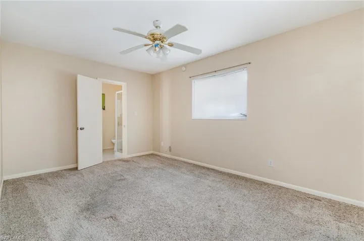 Empty room featuring light colored carpet and a ceiling fan