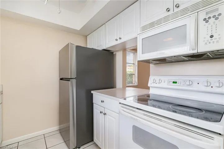 Kitchen featuring white appliances, white cabinetry, light countertops, and light tile patterned floors