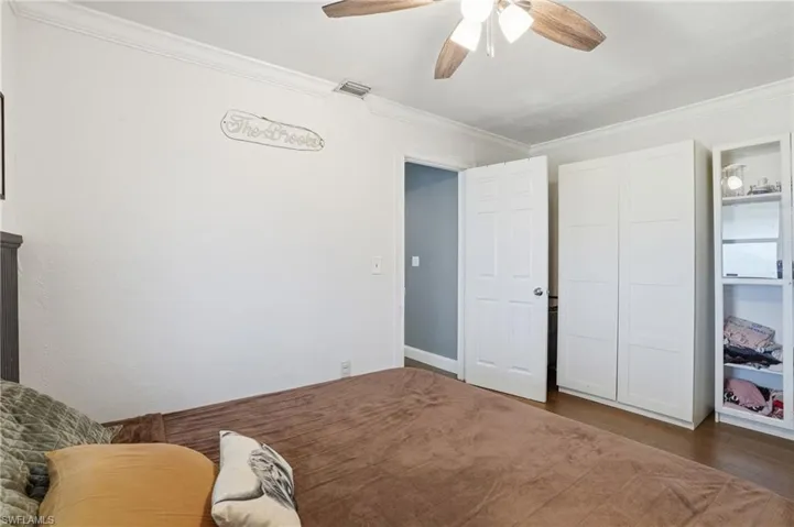 Bright interior space featuring wood-finish flooring, white paneled walls, and crown molding