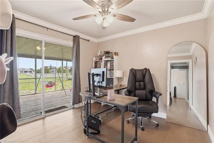 Room featuring wood-finish flooring, crown molding, and a ceiling fan