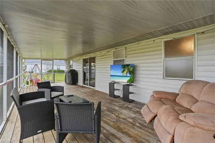 Expansive screened porch with wood-finish decking, white siding, and a white paneled ceiling