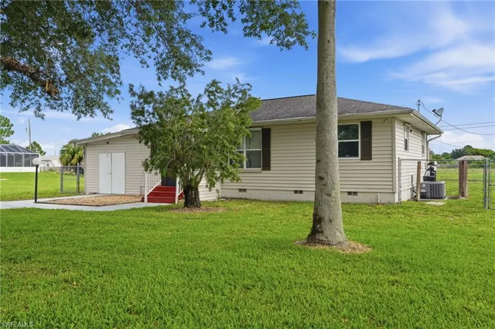 Exterior featuring beige siding, dark brown window shutters, and a dark shingle roof