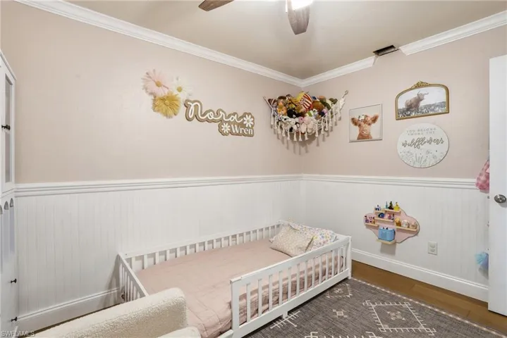 Room featuring wainscoting, crown molding, and wood-finish flooring