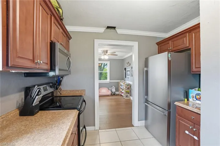 Kitchen featuring a stainless steel refrigerator, dark wood-finish cabinetry, a built-in microwave, and a black electric range
