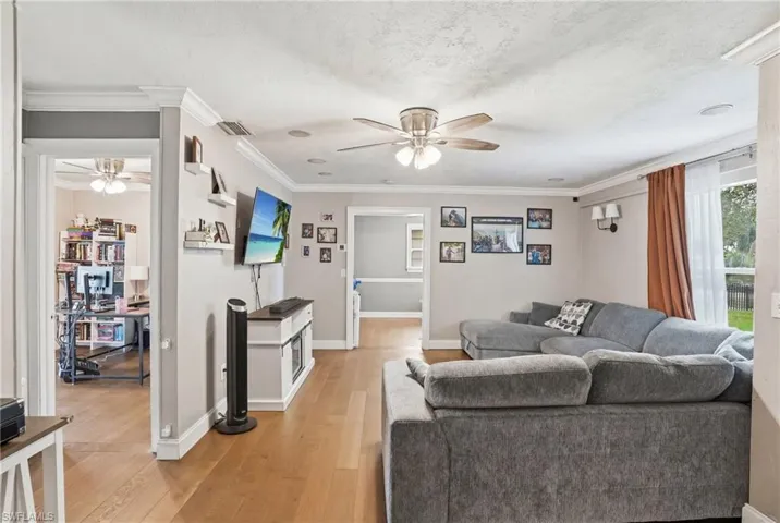 Open-concept living area featuring wood-finish flooring, crown molding, and recessed lighting