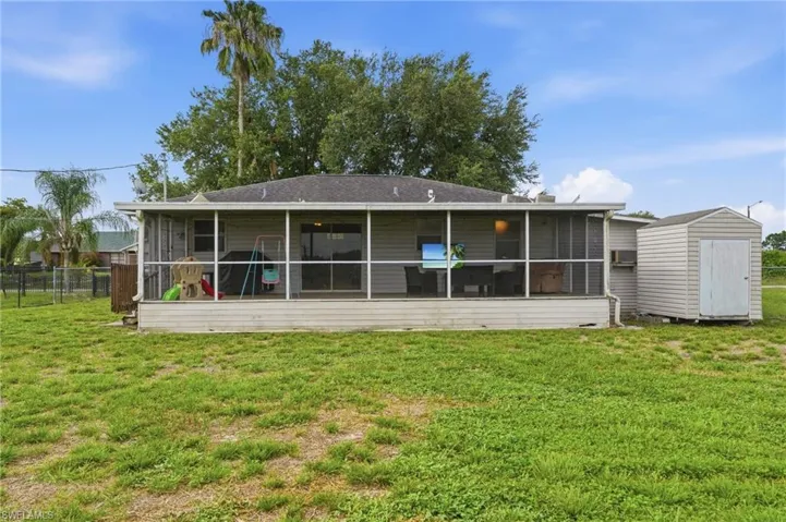 Rear exterior featuring a screened porch, sliding glass doors, and a detached storage shed